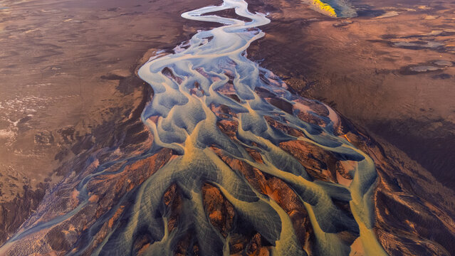 Aerial view of a braided river flowing through a volcanic landscape in Iceland.