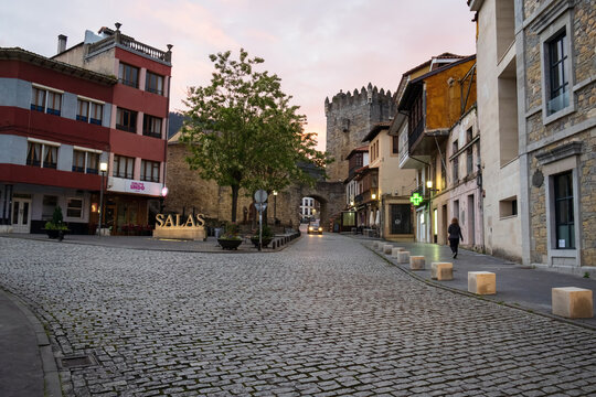 Salas, Asturias, Spain - May 15, 2025: Quiet cobblestone street leading to the medieval Torre de la Villa tower at dusk along the Camino Primitivo.