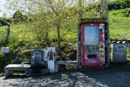 Asturias, Spain - August 2026: Traditional stone water fountain next to a modern vending machine on the Camino Primitivo pilgrimage route