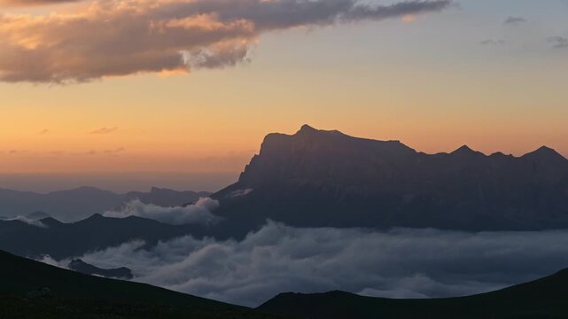 Mountain timelapse landscape at sunset with clouds rolling over the valley below