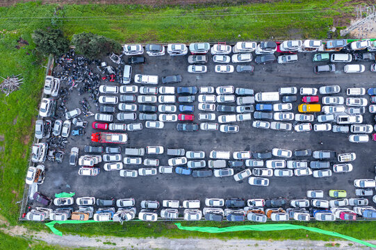 Aerial view of a wreckage yard filled with rows of damaged and salvaged cars parked on asphalt in Petah Tikva, Center District, Israel.