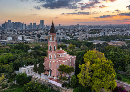 Aerial view of Saint Peter and Saint Tabitha Russian Orthodox Church amidst trees, with the Tel Aviv skyline in the background at sunset in Tel Aviv-Yafo, Tel Aviv District, Israel.