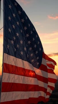 American Flag Waving at Sunset - A close-up shot captures the American flag billowing against a warm, colorful sunset sky.
