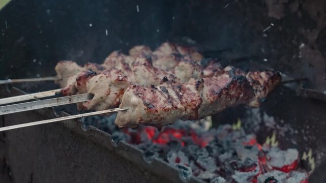 Fresh marinated meat grilling on metal skewers over hot charcoal and open flame
