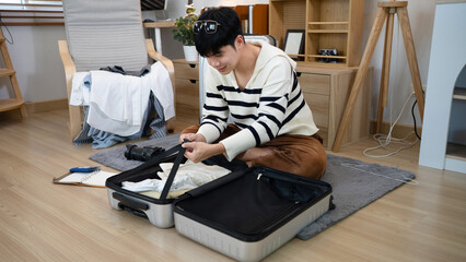 Man packing suitcase in home for travel, holiday trip and vacation. person in living room and prepare clothes in luggage bag for journey, solo adventure and leaving for tourism voyage © Stella 16