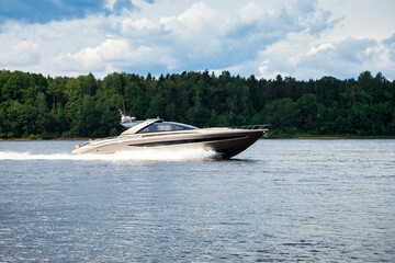 Fototapeta premium Luxury Speedboat Gliding Over Tranquil Waters Under a Cloudy Sky