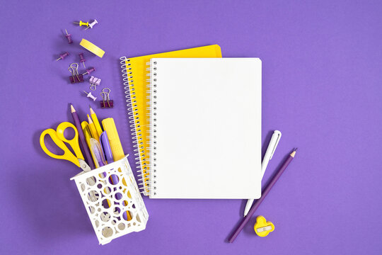 Yellow and Purple School Office Stationery Flat Lay Background. Blank Open Notebook with Scissors, Pencils, Pens and Clips on Violet Desk Top View. Creative Workspace, Back to School, Corporate  Conce