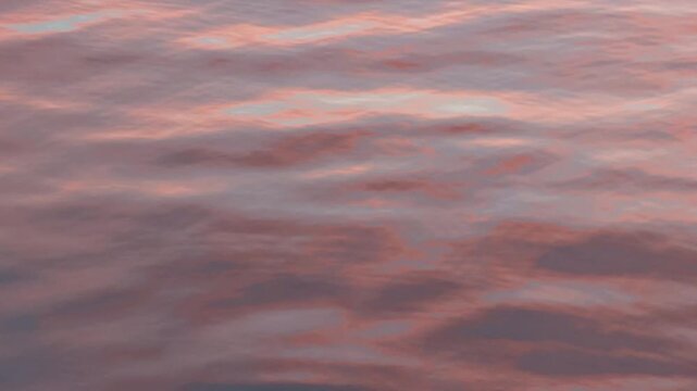 Close up abstract view of pink and mauve clouds forming a textured sky background at sunset