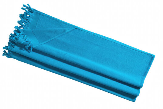 Top-down diagonal view of folded turquoise blue beach towel with fringe tassels on white background