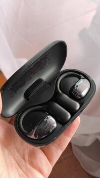 Woman holding wireless earbuds charging case, true wireless earphones, music listening and portable audio concept.