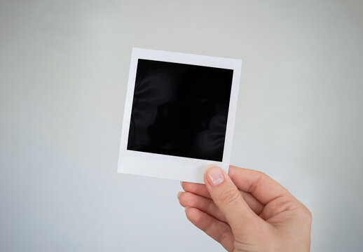 Instant photo in clean woman&rsquo;s hand Isolated on grey background Mockup. Generative ai