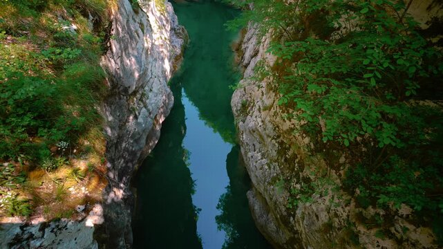 Deep turquoise water pool surrounded by massive canyon walls in Cellina gorge, Sentiero del Dint, Italy.