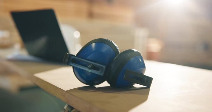 Earmuffs, carpentry and workshop with safety equipment, woodwork and noise reduction tech. Laptop, empty and tools on desk with ppe, ear protection or hearing damage prevention in joinery industry