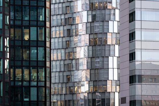 Across varied facades, vertical towers set bands of glass in sequence, while windows frame neighboring buildings in urban contrast as density shapes the architecture.