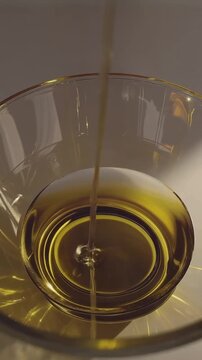 Olive oil pouring into clear glass bowl