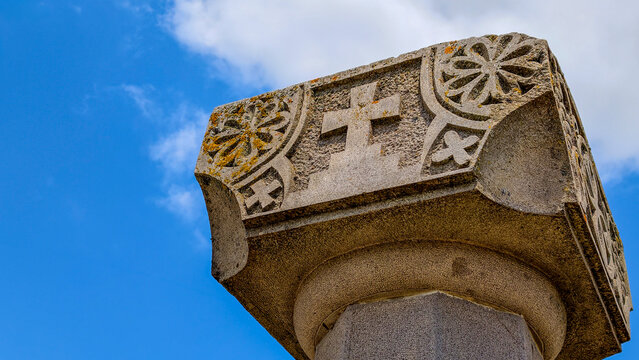 Stone pillar capital displaying intricate religious carvings. Including a distinctive armenian cross and decorative floral patterns