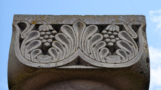 Ornate stone capital showcasing intricate carvings of grape bunches and stylized acanthus leaves, highlighting ancient craftsmanship and symbolic motifs of fertility and heritage