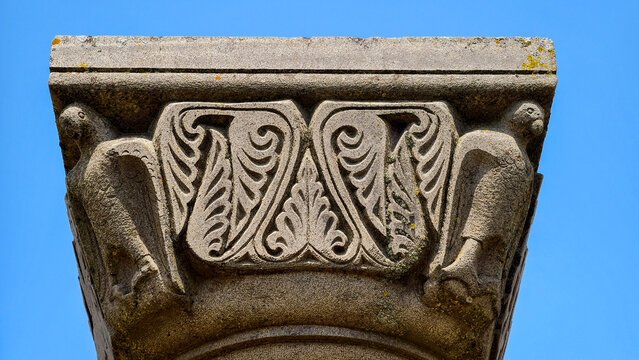 Elaborate stone capital showcasing detailed carvings of birds flanking an ornate central floral motif. Highlighting historical art. Skilled craftsmanship