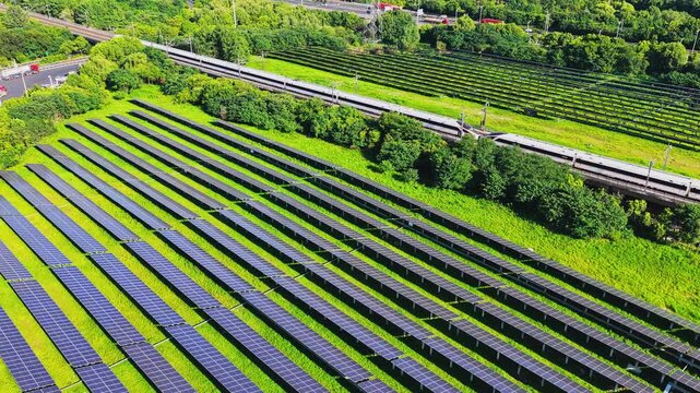 Aerial view of a high speed train beside a solar farm