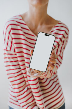 Woman In Striped Top Holding Smartphone At Angle Displaying Blank Screen Mockup For App Showcase