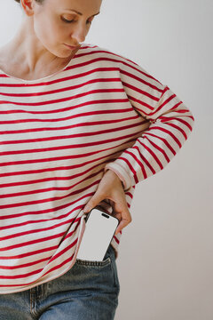 Female Model Placing Smartphone Screen Mockup Into Blue Jeans Pocket With Empty Space For Text