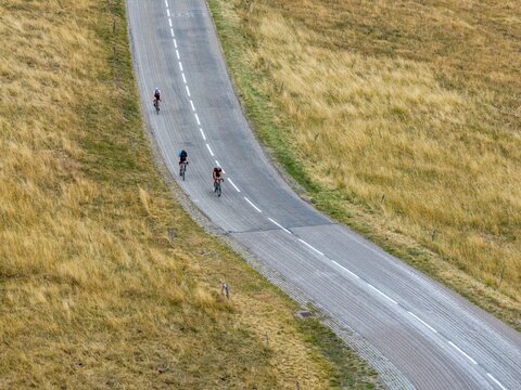 Aerial view of cyclists riding along a winding road on the slopes of Grand-Ballon in Soultz-Haut-Rhin, Grand Est, France.