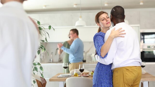  Multiethnic male and female couples slow dancing in kitchen