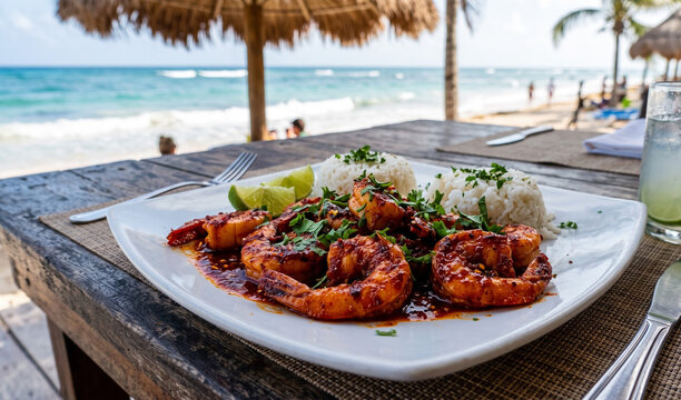 A rich plate of fiery red Camarones al Diablo served on a crisp white square ceramic plate, Plump jumbo shrimp coated in a glossy, spicy red habanero-chipotle sauce, garnished with fresh lime wedges a