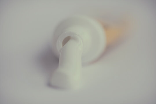 Close-up of toothpaste oozing out of an open toothpaste tube on a table