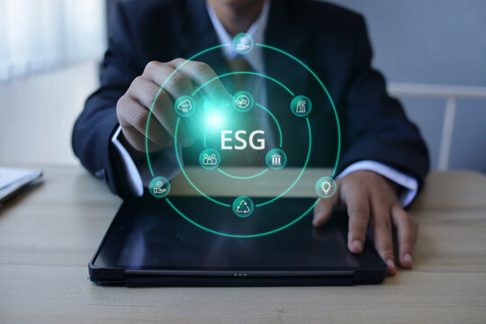 Businessman Pointing at ESG Hologram With Tablet on Office Desk