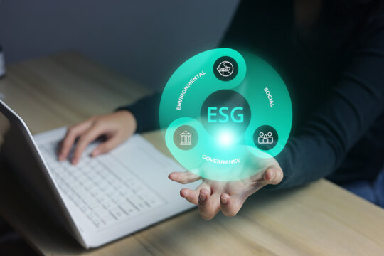 Hand Typing on Laptop While Holding ESG Swirl Hologram Above Open Hand Over Desk