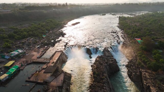 Jabalpur, Madhya Pradesh, India - April 01, 2026: Drone footage smoothly tilting downward to reveal Dhuandhar Waterfall, the Narmada River, marble gorge, rocky cliffs, and riverside at Bhedaghat.