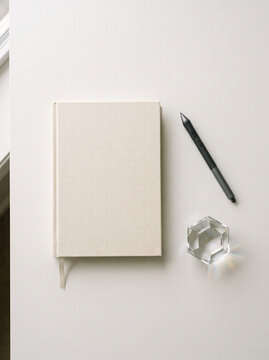 Linen Notebook with Stylus Pen and Crystal Paperweight on White Desk