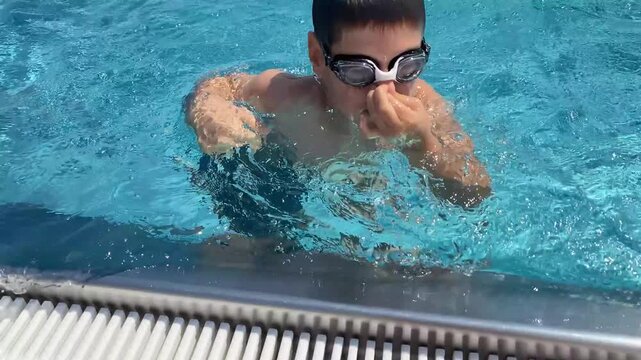 Child holding nose and diving into swimming pool water