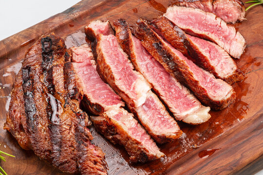 Sliced grilled beef ribeye steak medium rare on wooden cutting board