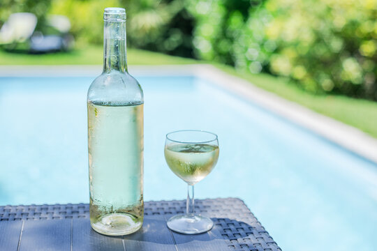 Bottle and one glass of white wine on outdoor table