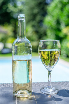 Bottle and two glasses of white wine on outdoor table