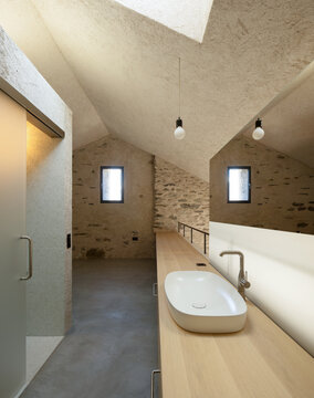 A large bedroom with a washbasin and an adjoining shower. No one inside. Modern architecture in an old house.