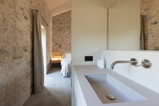 The interior of a bathroom in a bedroom. A very small but romantic space. A grey, brand-new washbasin.
