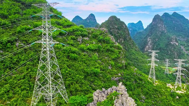 High-voltage transmission towers cross the lush karst mountains of Guilin, China, highlighting infrastructure amid a scenic limestone landscape.