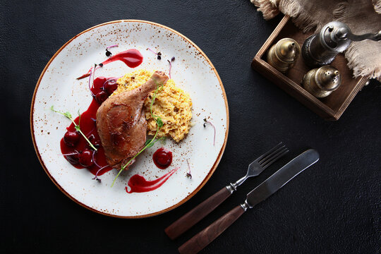 Baked duck leg with cherry sauce. An exquisite dish. Slices of white bread. Top view.