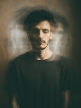 Conceptual portrait of a calm man with a motion-blurred ghost effect around his head representing mental health, anxiety, and internal noise.