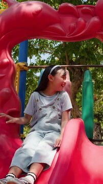 Happy Thai Girl Playing on Red Slide at Lumpini Park
