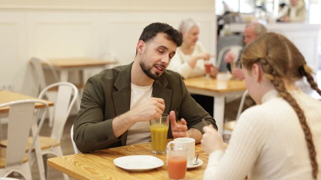 Father and teenage daughter sitting at table in cafe. Light snack or coffee break at restaurant, family getaway or pastime. Family time, Sunday lunch at chain cafe in capitals pedestrian tourist area.
