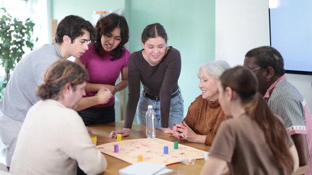 Engaged men and women of different ages playing tabletop game during interactive workshop indoors