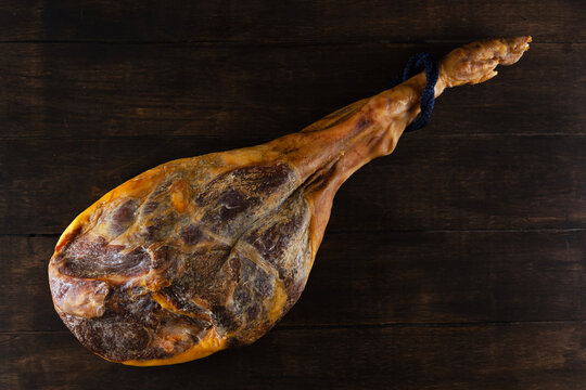 Top view of dried hamon leg (jamon) with blue rope lying on dark textured wooden surface