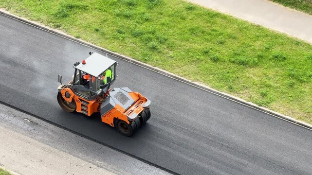 Road roller compacts a smooth asphalt lane on a rural highway, infrastructure investment, efficient transport, engineering progress, aerial construction view.