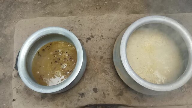 Traditional Indian Dal and Rice Cooking in Aluminum Pots on Floor