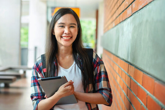 Young woman smiles warmly, holding tablet