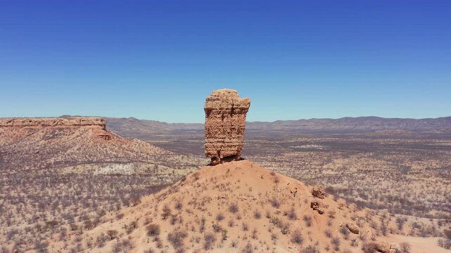 Slow panoramic drone pan of Fingerklippe rock needle, Namibia at midday. Dry barren landscape, leafless trees, clear cloudless sky
